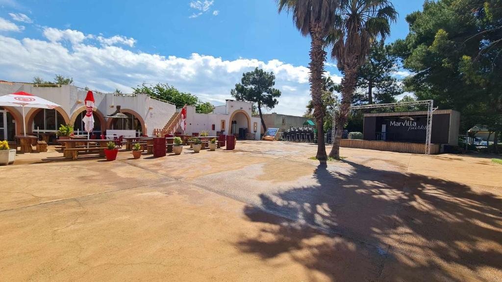 un parc avec des bancs et un bâtiment avec un palmier dans l'établissement Mobil Home récent Camping La Palmeraie, à Torreilles