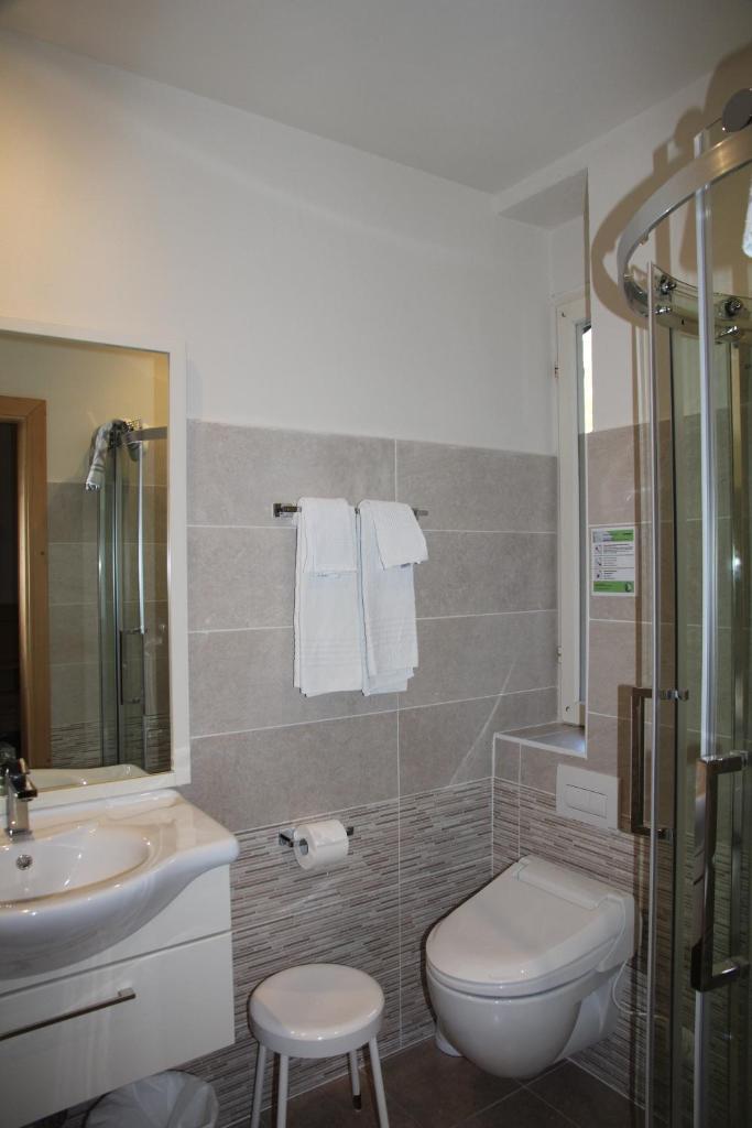 une salle de bain avec toilettes, lavabo et douche dans l'établissement Lago Park Hotel, à Molveno