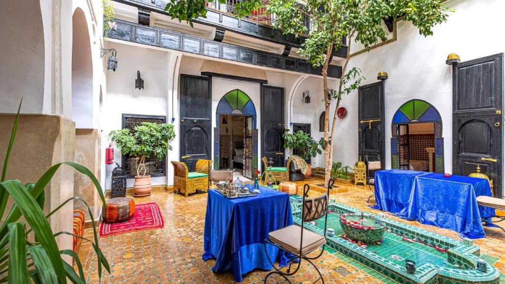 une cour avec des tables et des chaises dans un bâtiment dans l'établissement Riad ABBASSIA Marrakech Premiere, à Marrakech