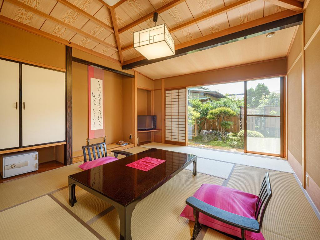 un salon avec une table et une grande fenêtre dans l'établissement Sekitaitei Ishida, à Achi