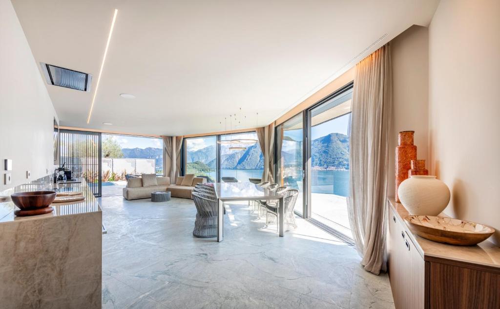 - un salon avec une table, des chaises et des fenêtres en verre dans l'établissement Villa Osee Lago di Como, à Sala Comacina