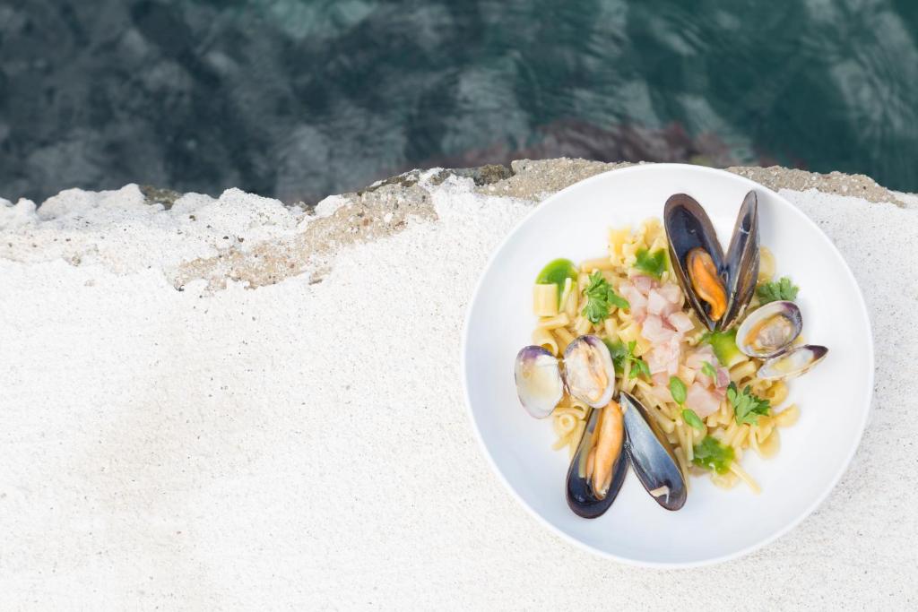 une assiette de nourriture avec des moules et des légumes sur une plage dans l'établissement Pagoda Lifestyle Hotel, à Ischia