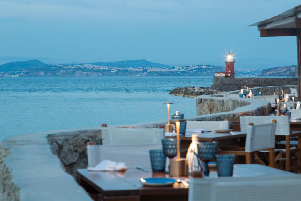 un restaurant avec vue sur l'eau et un phare dans l'établissement Pagoda Lifestyle Hotel, à Ischia