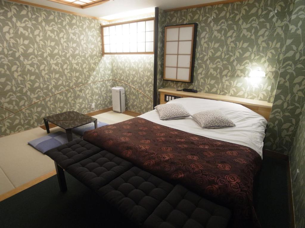 - une chambre avec un lit et un banc dans l'établissement ホテルラパンセ Adult Only, à Saitama