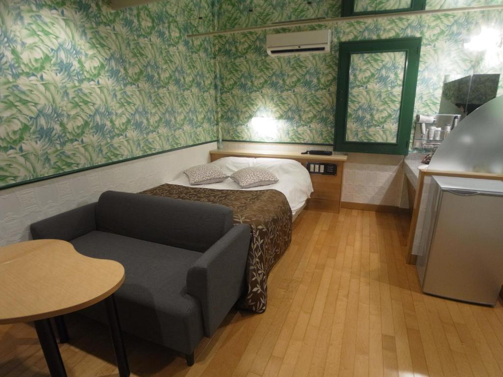 Cette petite chambre comprend un lit, une chaise et une table. dans l'établissement ホテルラパンセ Adult Only, à Saitama