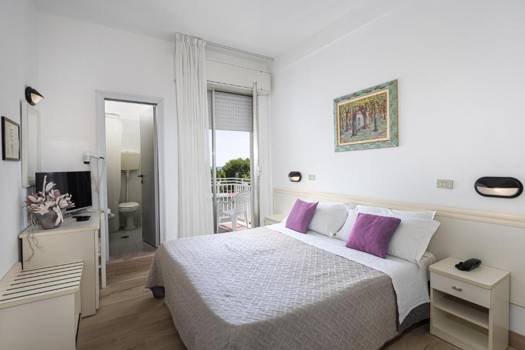 - une chambre blanche avec un lit et des oreillers violets dans l'établissement Hotel Gioiello, à Cesenatico 29 autres photos