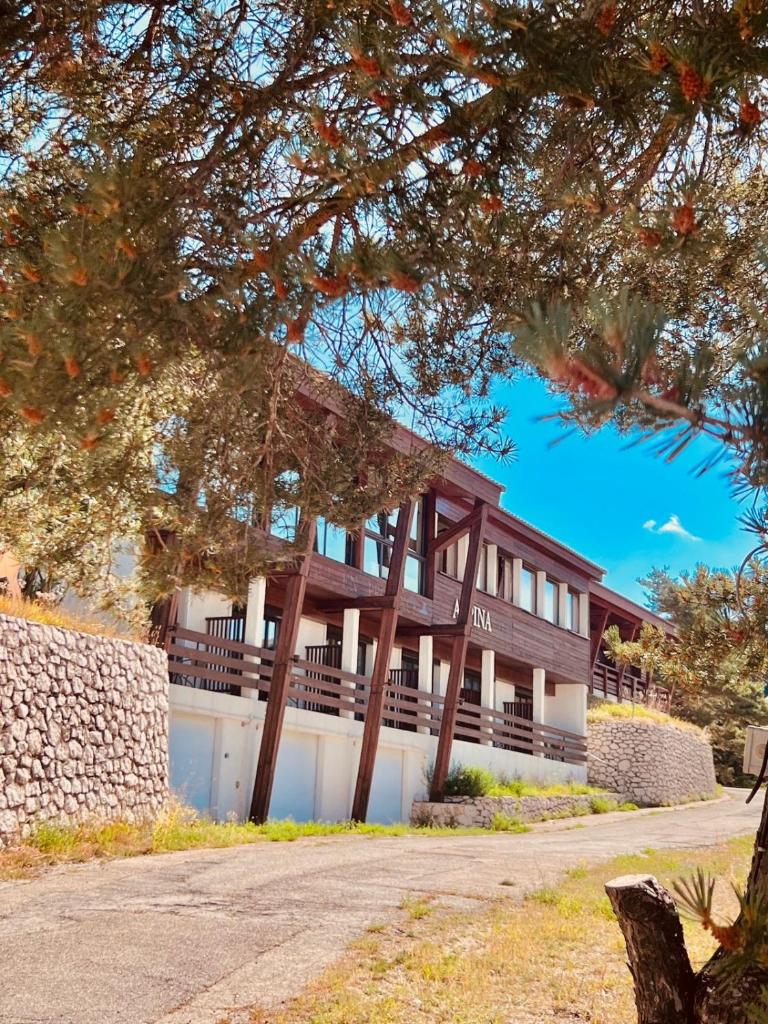 un bâtiment avec un arbre devant lui dans l'établissement Auberge Alpina, à Gréolières