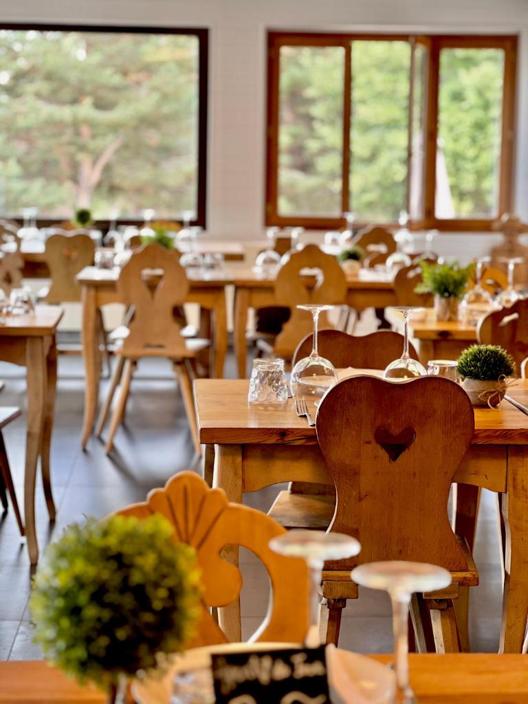 Cette chambre dispose de tables et de chaises en bois ainsi que de fenêtres. dans l'établissement Auberge Alpina, à Gréolières