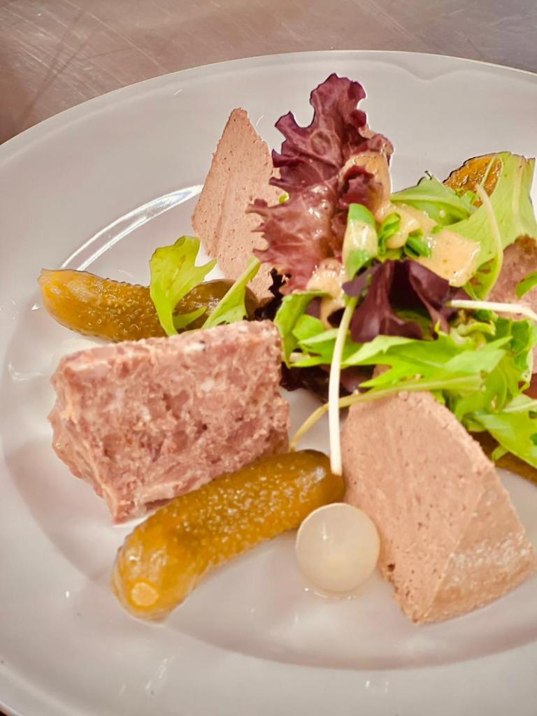une assiette de nourriture avec une salade et un pickle dans l'établissement Auberge Alpina, à Gréolières 26 autres photos