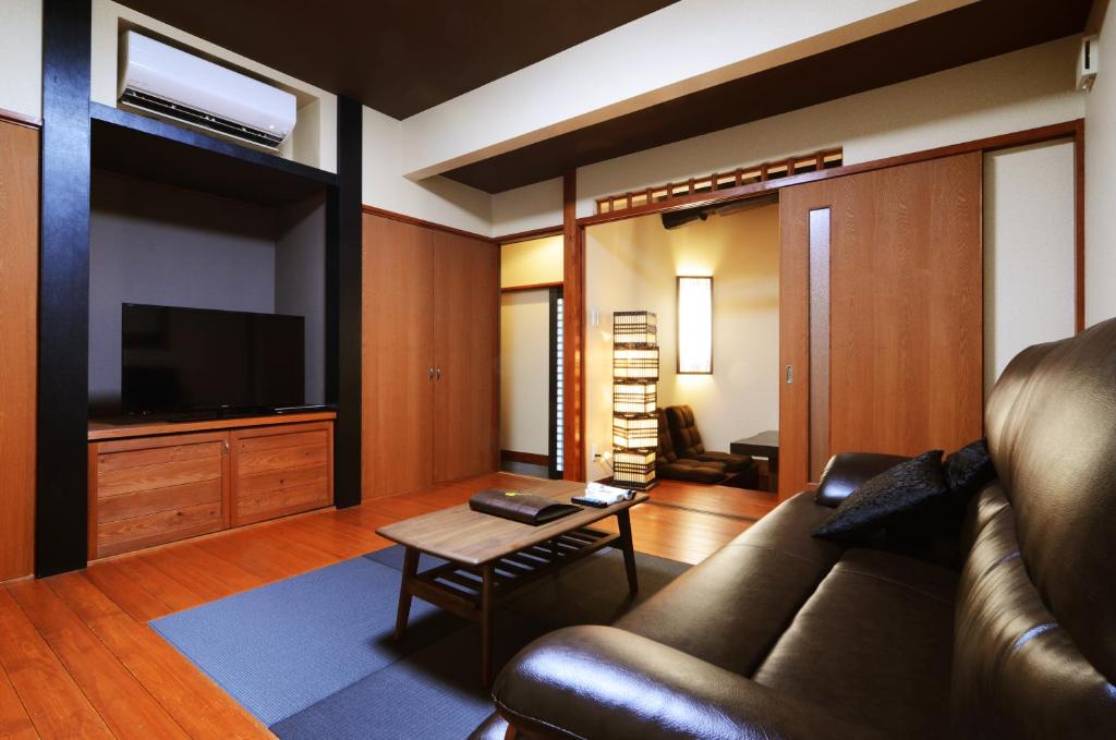 un salon avec un canapé et une télévision dans l'établissement 徳の宿 ふぶ庵, à Beppu