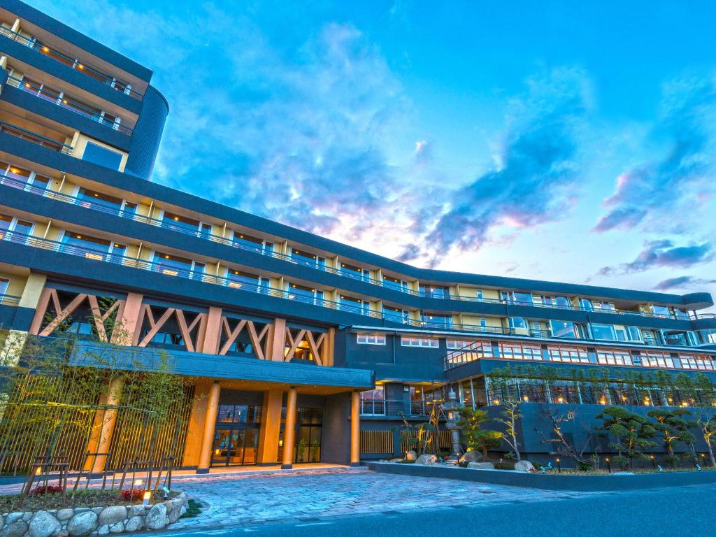 un grand bâtiment avec un coucher de soleil en arrière-plan dans l'établissement Ooedo Onsen Monogatari Premium Shirahama Gyoen, à Shirahama