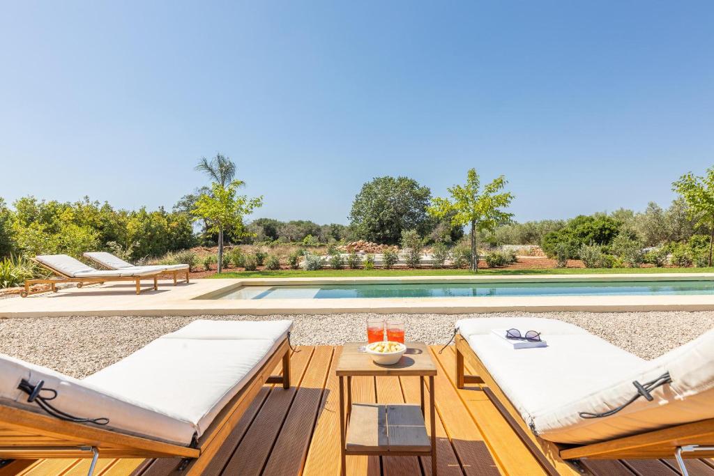 une piscine avec deux chaises longues et une piscine dans l'établissement Tenuta del Leccino, à Torre Vado