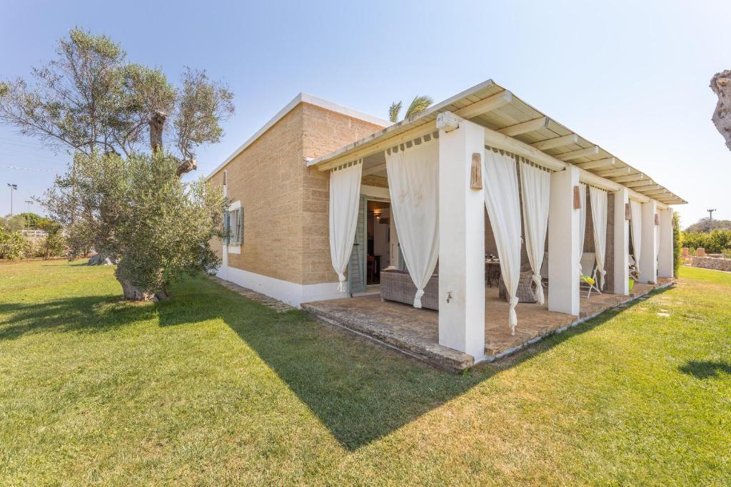 une maison avec des rideaux blancs dans une cour dans l'établissement Tenuta del Leccino, à Torre Vado