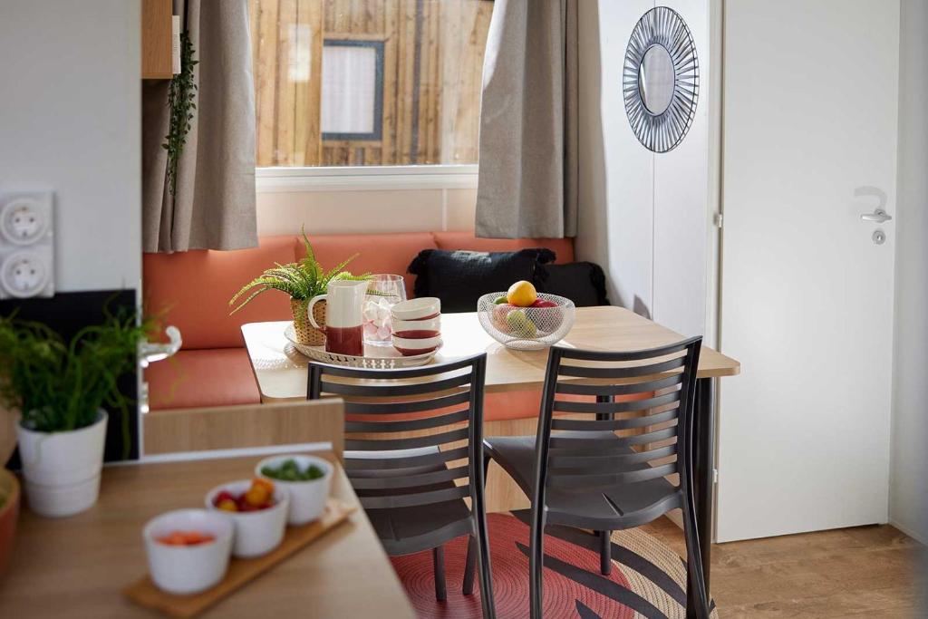 - une table à manger avec 2 chaises et une table avec des fruits dans l'établissement Lodges & Nature - 71, à Avignon
