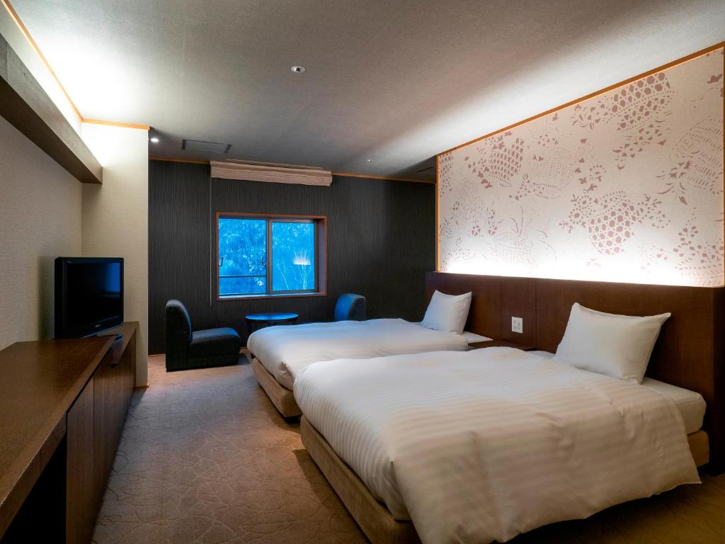 une chambre d'hôtel avec deux lits et une télévision dans l'établissement 層雲閣, à Kamikawa