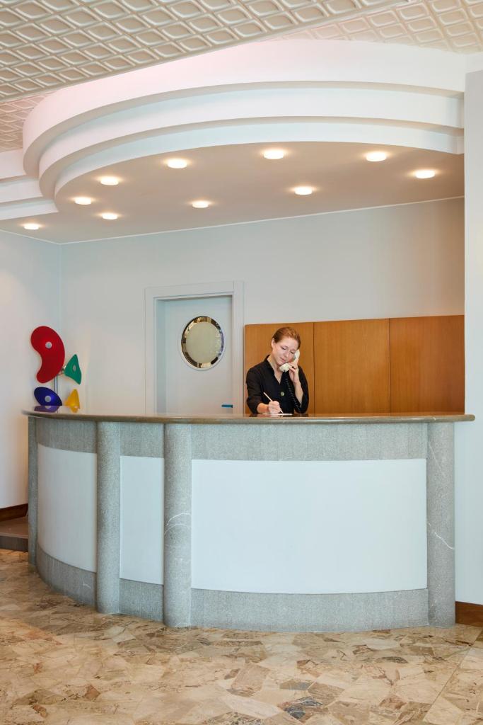 un homme parlant sur un téléphone à un comptoir dans une pièce dans l'établissement Termini Beach Hotel & Suites, à Lido di Jesolo 67 autres photos