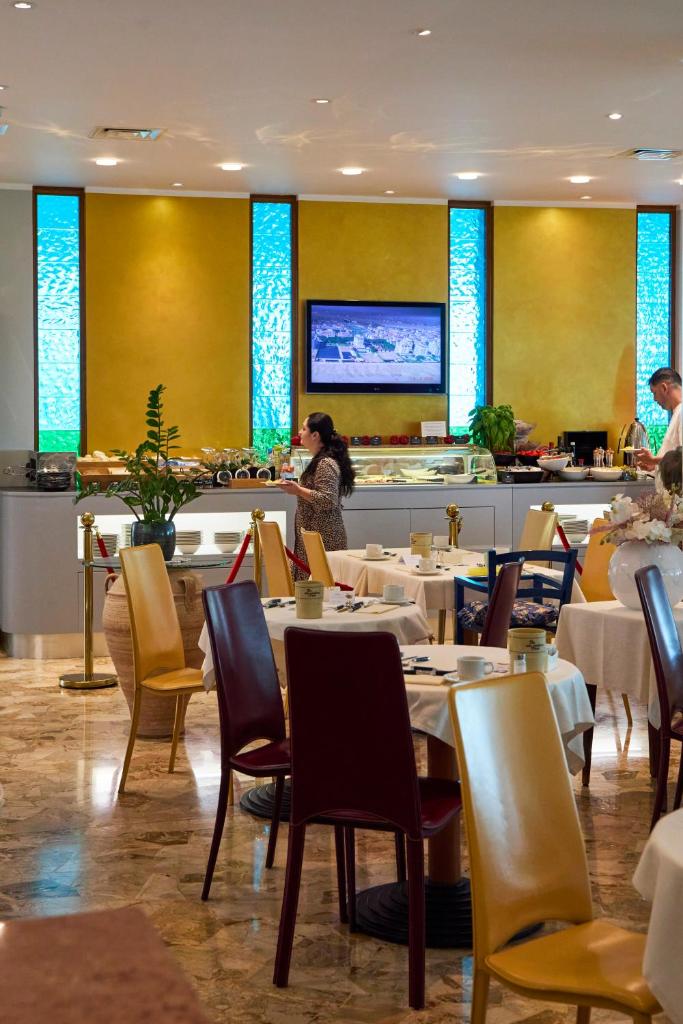 un restaurant avec des tables, des chaises et un comptoir dans l'établissement Termini Beach Hotel & Suites, à Lido di Jesolo