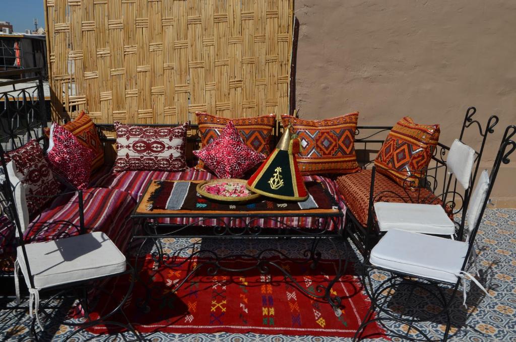 - un canapé avec des oreillers, une table et des chaises dans l'établissement Riad Benrahal, à Marrakech