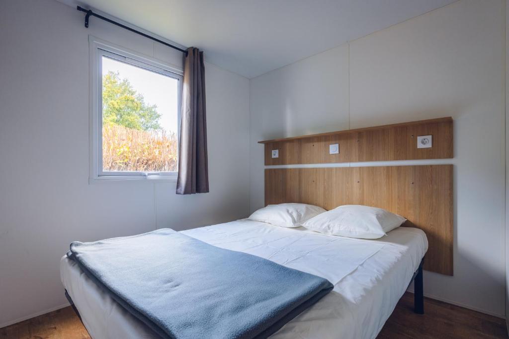 une chambre avec un grand lit avec une fenêtre dans l'établissement L'Oasis des Dombes, à Ambérieux-en-Dombes