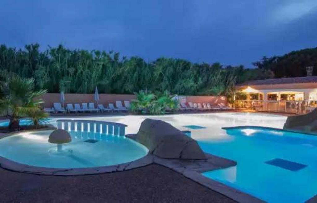 - une grande piscine d'eau bleue la nuit dans l'établissement Camping 4 étoiles - Parc aquatique - eebadc, à Bormes-les-Mimosas