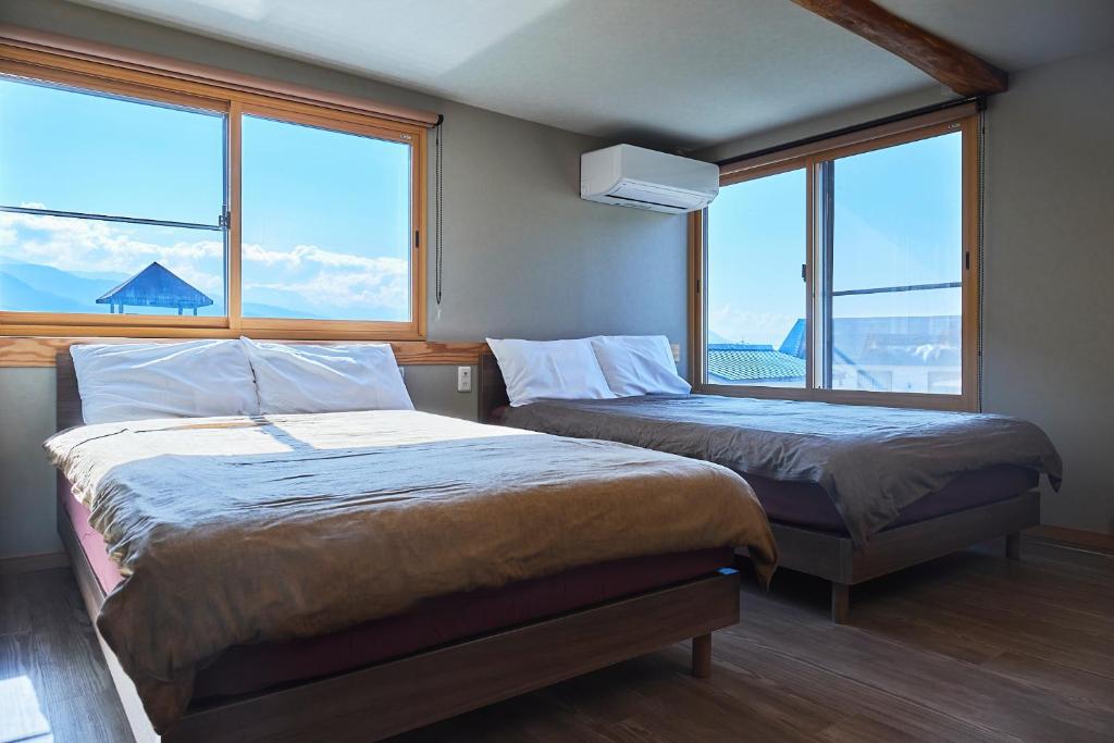 - 2 lits dans une chambre avec de grandes fenêtres dans l'établissement メイプルハイム, à Iiyama
