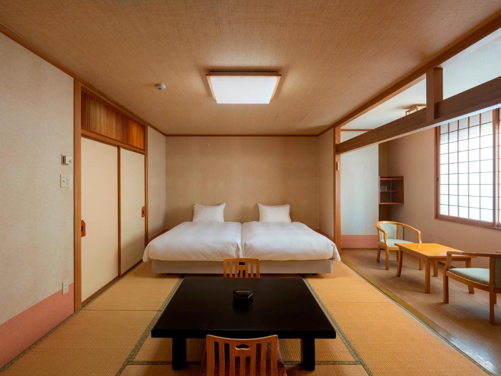 une chambre avec un lit et une table dedans dans l'établissement 層雲閣, à Kamikawa