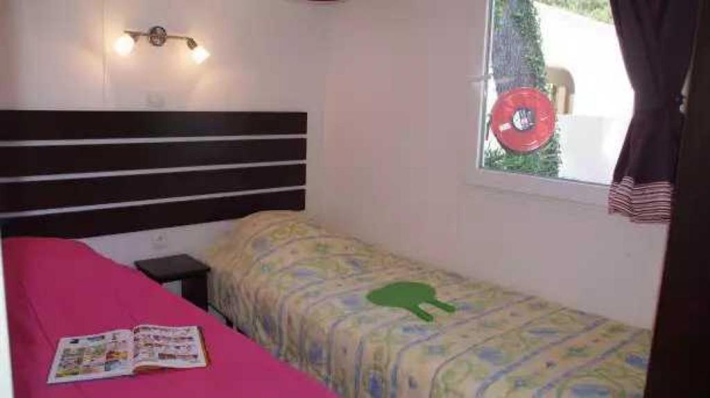 une petite chambre avec un lit rose et une fenêtre dans l'établissement Camping 4 étoiles - Parc aquatique - eebadc, à Bormes-les-Mimosas