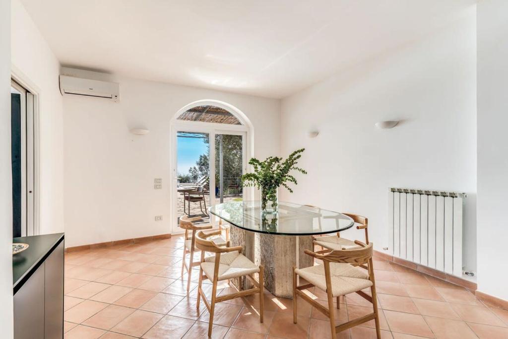 une salle à manger avec une table et des chaises en verre dans l'établissement Villa Chez Piè Panoramic Views Pool and Guest Services, à SantʼAgata sui Due Golfi
