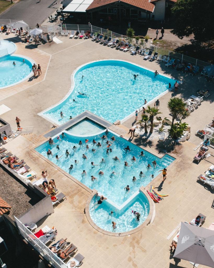 - une vue de tête sur deux piscines avec des personnes dans l'établissement Camping Lou Broustaricq, à Sanguinet