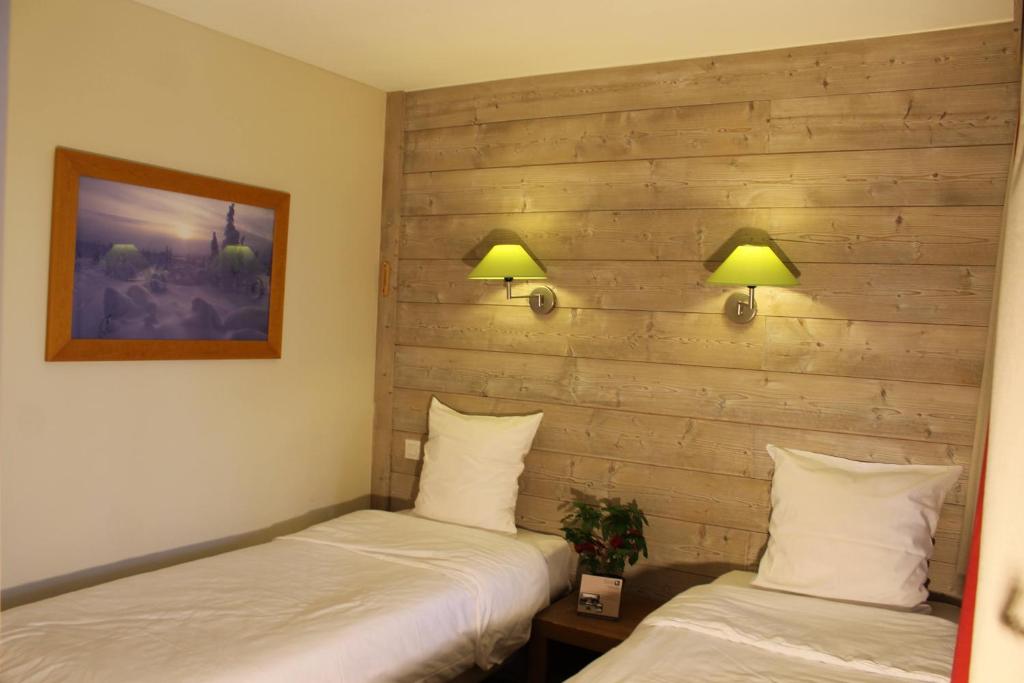 - 2 lits dans une chambre avec 2 lampes sur le mur dans l'établissement Résidence Christiana 307 Clés Blanches Courchevel, à Courchevel
