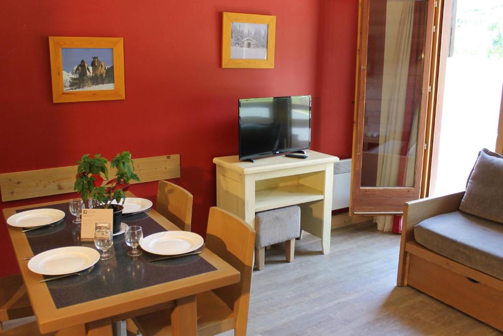 un salon avec une table et une télévision dans l'établissement Résidence Christiana 408 Clés Blanches Courchevel, à Courchevel