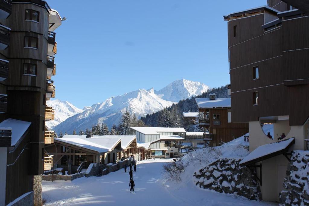 un groupe de bâtiments dans la neige avec des montagnes dans l'établissement Résidence Christiana 408 Clés Blanches Courchevel, à Courchevel