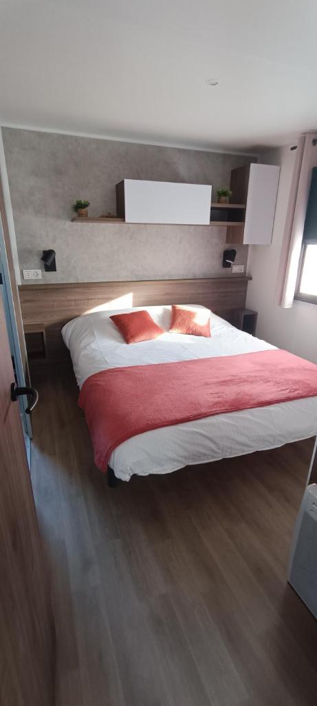 une chambre avec un grand lit avec une couverture rouge dans l'établissement Mobil home chez Véronique, à Canet
