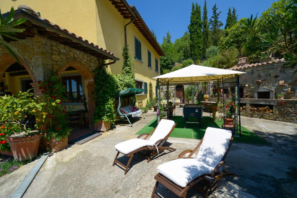 un patio avec deux chaises et un parasol dans l'établissement Villa Le Celle Del Farinaio, à Cortone