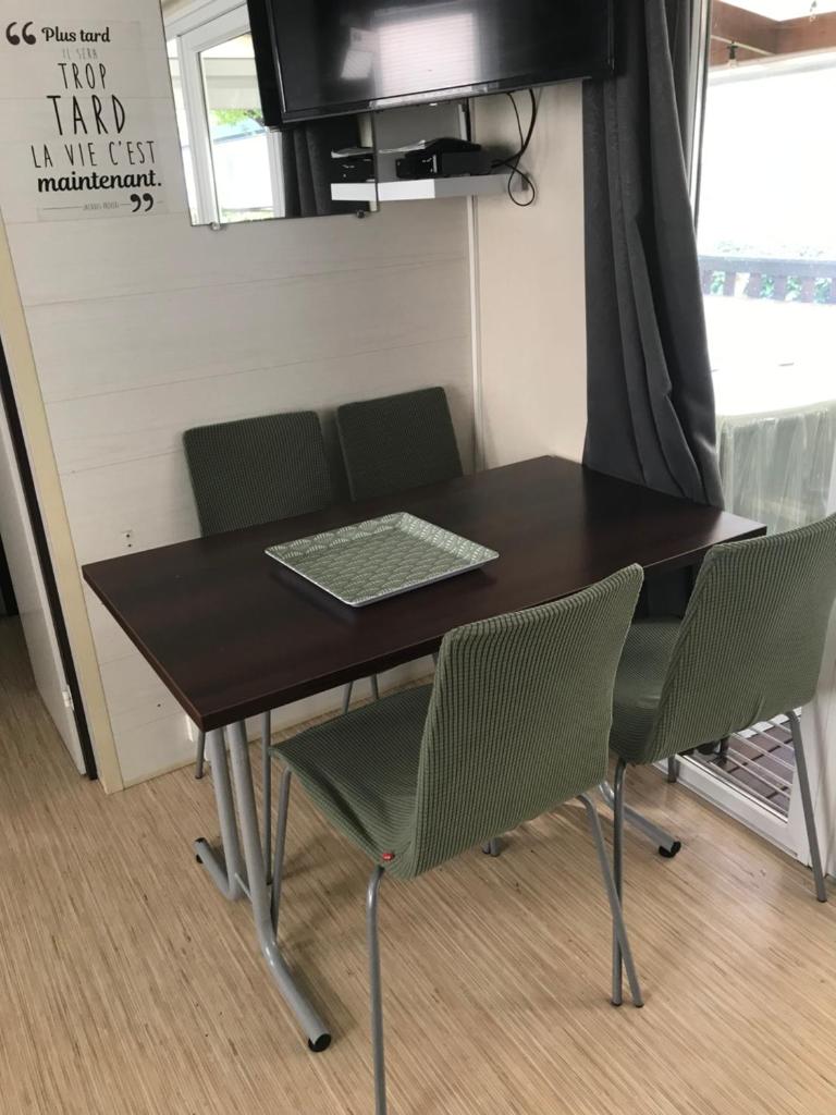 une table à manger avec des chaises et une télévision dans l'établissement Mobilhome confort, à Bias 4 autres photos