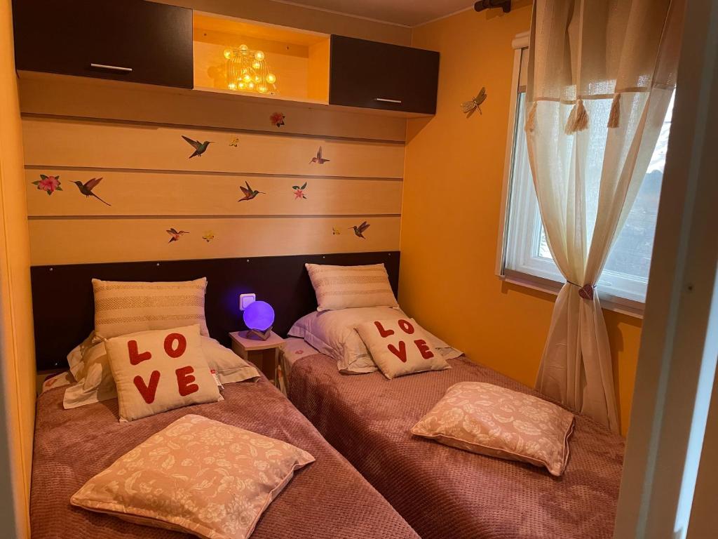 deux lits jumeaux dans une chambre avec fenêtre dans l'établissement Coquet mobilehome 8 places, à Puget-sur Argens