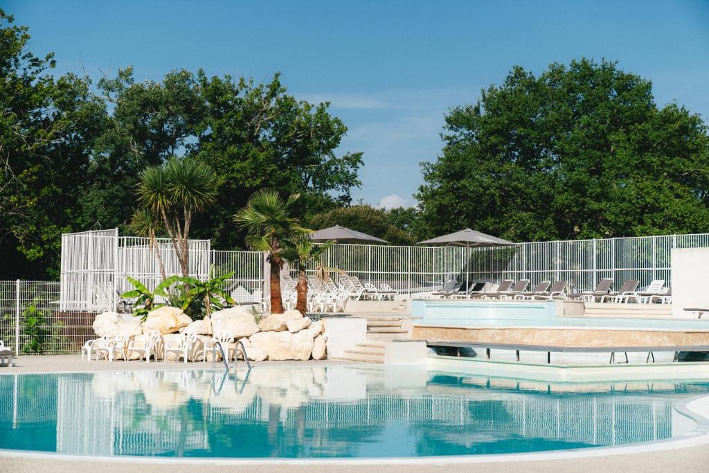 une piscine dans un complexe hôtelier avec chaises et parasols dans l'établissement Camping Lou Broustaricq, à Sanguinet