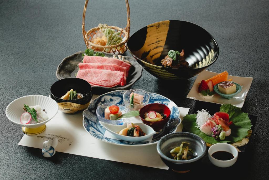 une table recouverte de assiettes de nourriture et de bols de sushis dans l'établissement onogawaonsen azumasou, à Yonezawa