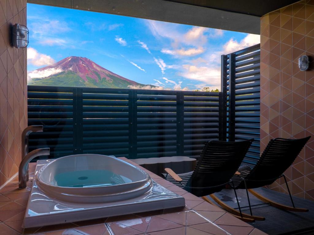 une chambre avec une baignoire, des chaises et une montagne dans l'établissement Mt Fuji View and Private Sauna Ryokan Shizuku, à Yamanakako