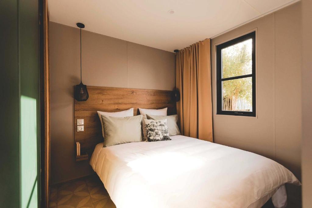 une chambre avec un grand lit blanc avec une fenêtre dans l'établissement Mobil Homes Vacances, à Grimaud