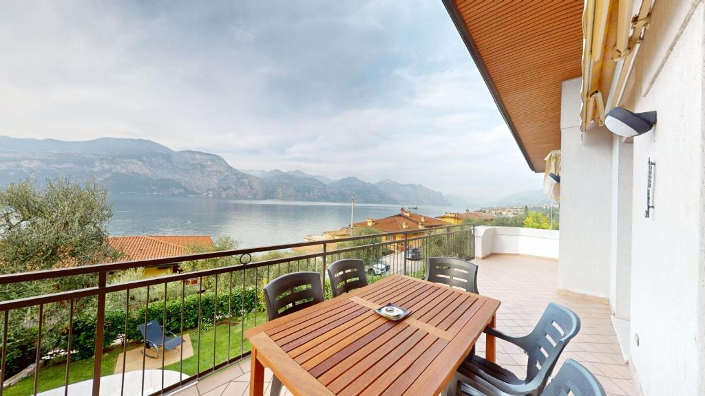 d'un balcon avec une table et des chaises en bois et une vue sur le lac. dans l'établissement Villa Mimosa-Con piscina e vista lago, à Brenzone
