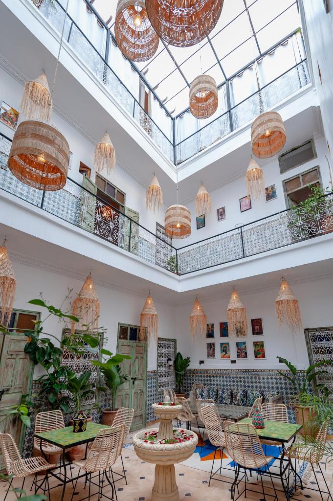 une grande pièce avec des tables, des chaises et des lustres dans l'établissement Riad Bab Taghzout Marrakech, à Marrakech