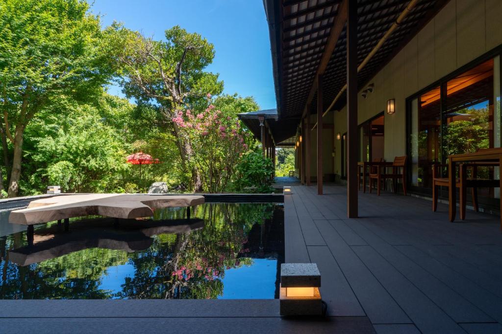 une piscine d'eau à côté d'un bâtiment arboré dans l'établissement Gyokusui -Adult Only-, à Higashiizu