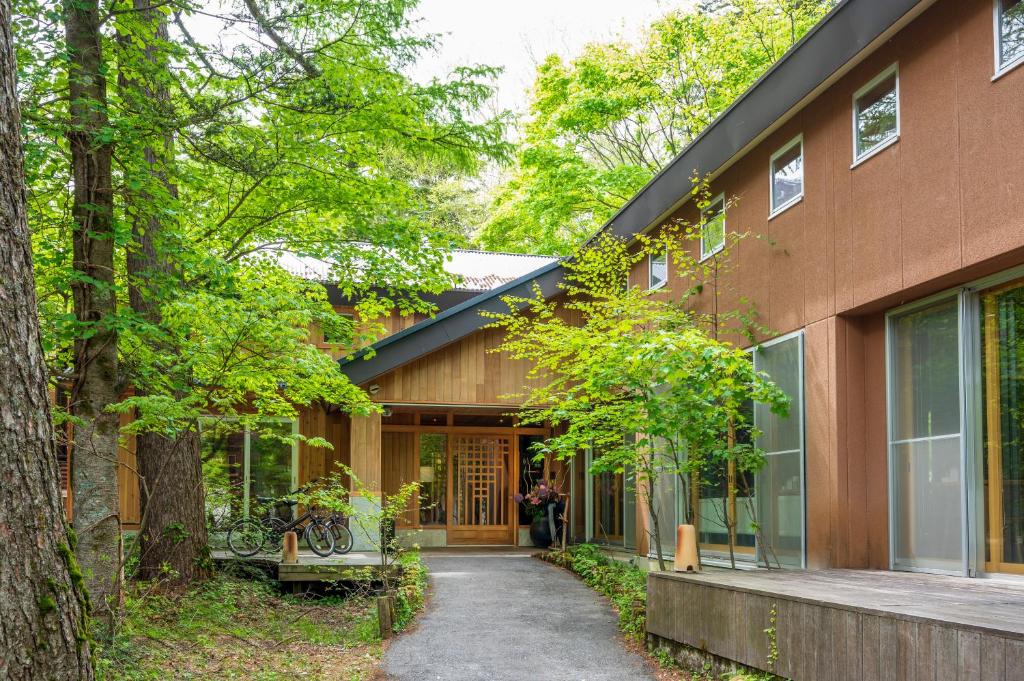 une maison dans les bois avec une personne debout devant elle dans l'établissement 奥日光湯元温泉ゆの森, à Nikkō