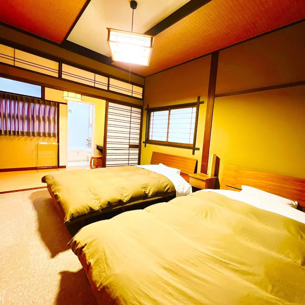 - 2 lits dans une chambre aux murs jaunes dans l'établissement Japanese style hotel and dining Morigen, à Kyōtango