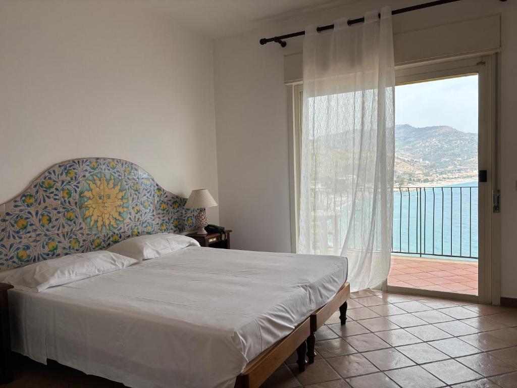 une chambre avec un lit et une grande fenêtre dans l'établissement Bay Palace Mazzarò, à Taormine