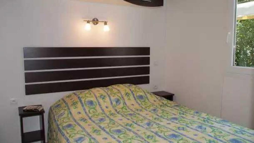 une chambre avec un lit avec une tête de lit en bois dans l'établissement Camping 4 étoiles - Parc aquatique - eebadc, à Bormes-les-Mimosas
