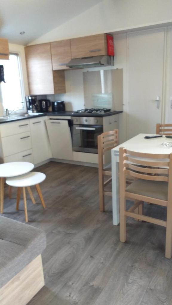 une cuisine avec des armoires blanches et une table et des chaises dans l'établissement MH 538 TOUT EQUIPE et TOUT CONFORT 2ch 1sdb dans camping 4 étoiles, à Saint-Julien-en-Born