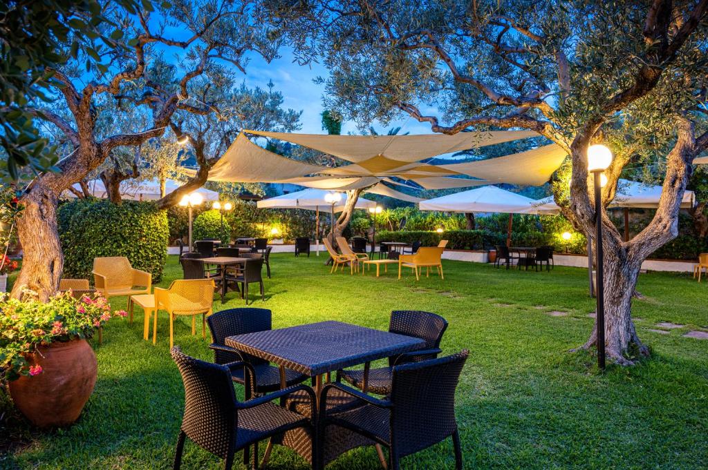 un patio avec tables, chaises et parasols dans l'établissement Hotiday Cefalù Mazzaforno, à Cefalù