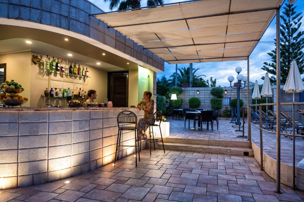 - un bar sur une terrasse avec une femme assise au comptoir dans l'établissement Hotiday Cefalù Mazzaforno, à Cefalù